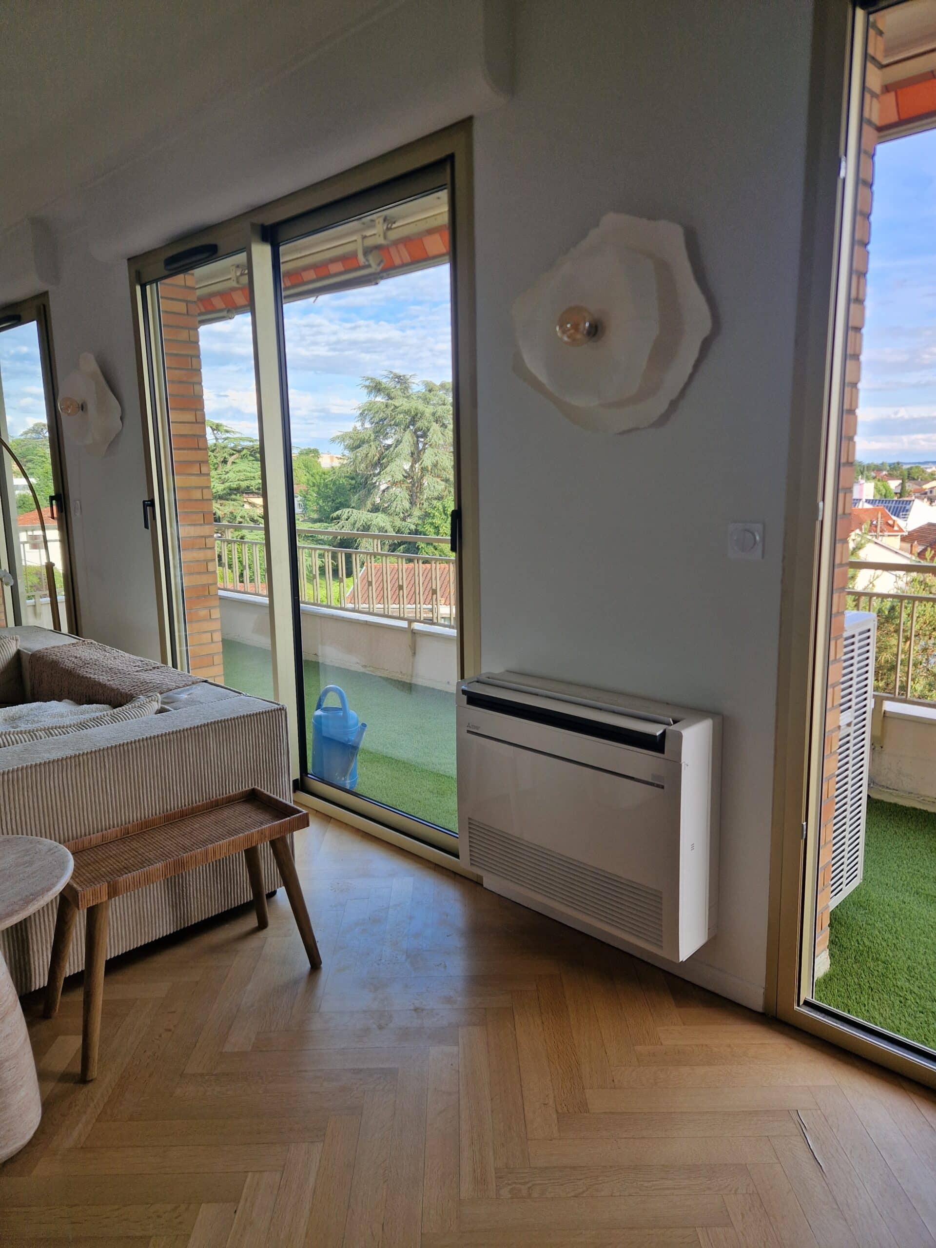 Salon moderne avec climatiseur et balcon ensoleillé Salon moderne avec parquet, climatiseur mural et grande porte-fenêtre ouvrant sur un balcon en gazon synthétique.